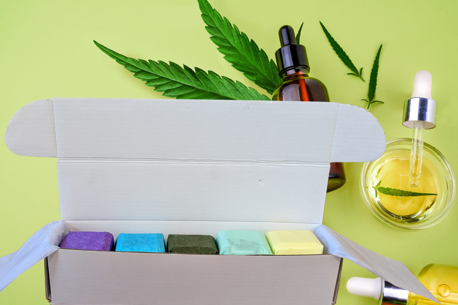 CBD shower steamers gift set inside a box with essential oils and hemp leaves on a bright background.