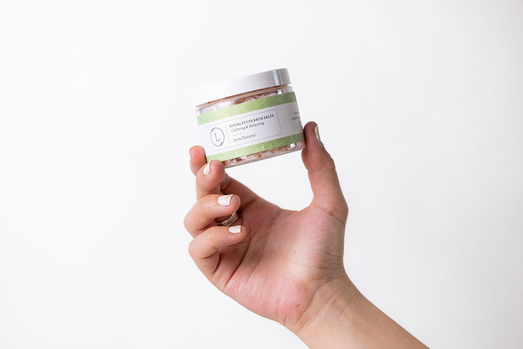 Person holding CBD Natural Eucalyptus Bath Salts in a jar, promoting relaxation and skin benefits, THC free.