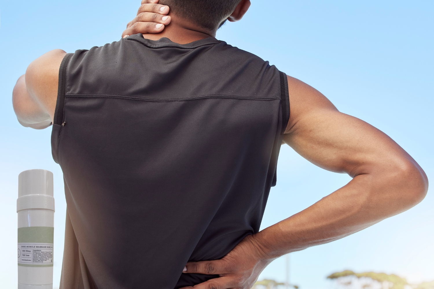 Man with back pain reaching for his neck outdoors, showcasing the need for muscle relief solutions.