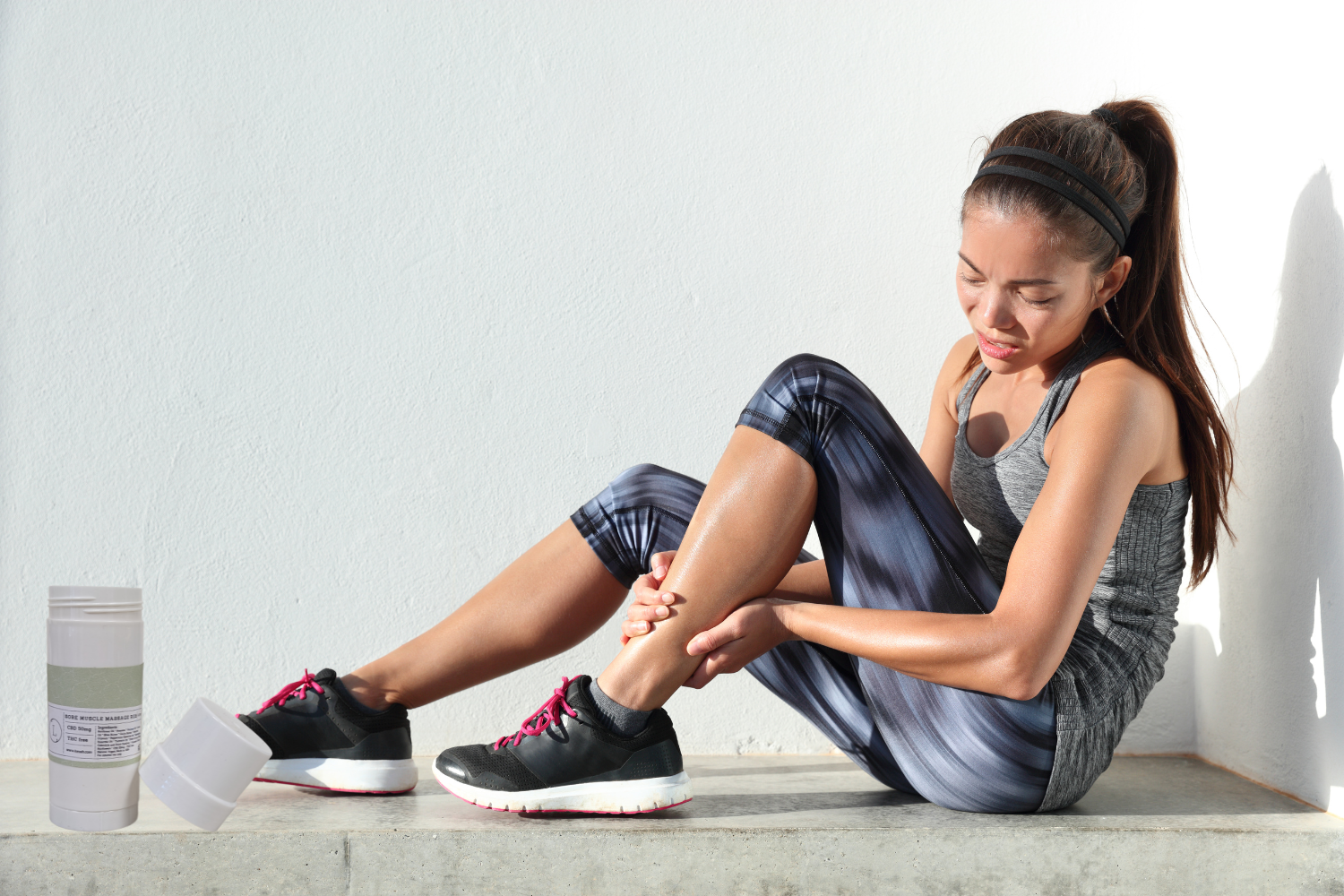 Woman applying CBD Muscle Rescue Balm to sore ankle after workout for muscle relief and relaxation.