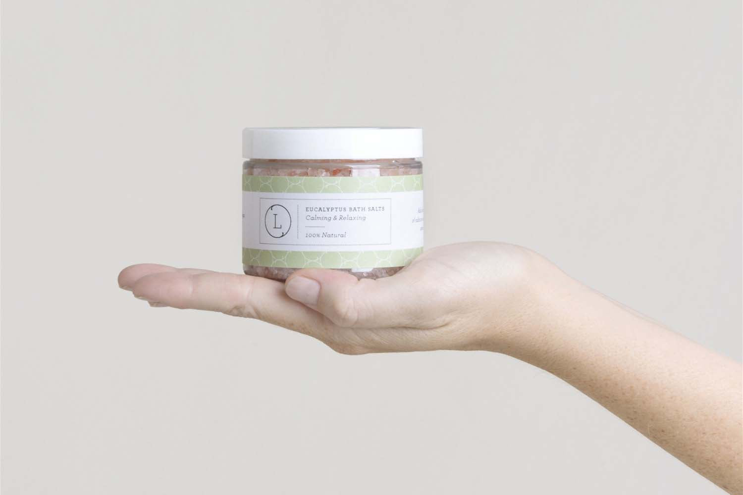 Hand holding jar of CBD natural eucalyptus bath salts, calming and relaxing, THC free.